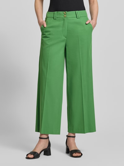 Frauenmodel trägt Wide Leg Hose aus Viskose-Mix mit Bügelfalten von More & More in Grün, glatte Textur, Mittellang, Nahaufnahme Unterkörper. Damen Hose Viskose-Mix mit Baumwoll-Anteil, Knopf- und Reißverschluss, Bundweite 39 cm, Innenbeinlänge 66 cm.