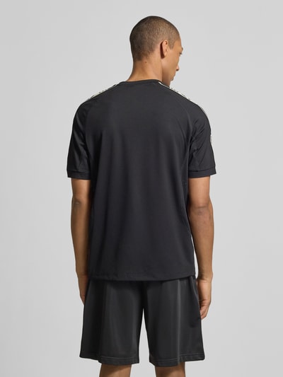 Męski model nosi T-shirt aus Viskose-Mix mit Logo von EA7 Emporio Armani, kolor czarny, krój regular fit, okrągły dekolt, długość tyłu 70 cm w rozmiarze M, widok całej sylwetki z tyłu.