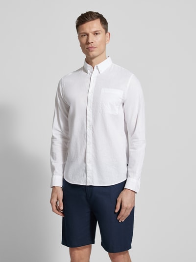Męski model nosi Regular Fit Freizeithemd mit Leinen-Anteil od Matinique, biały kolor, kieszeń na piersi, bawełna z lnem, krój regular fit, kołnierzyk button-down, długość tyłu w rozmiarze M: 64 cm, szerokość w rozmiarze M: 43 cm, długość rękawa w rozmiarze M: 68 cm, całkowity widok z przodu.