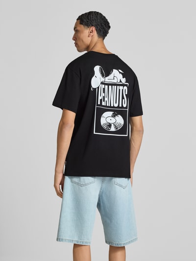 Männermodel trägt oversized t-shirt aus reiner baumwolle modell 'PEANUTS' von ONLY, zwart met witte print, heren t-shirt van ONLY, ganzkörperansicht rückansicht