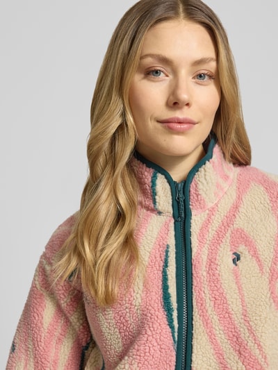 Kobiece model prezentuje kurtkę z polaru 'Fleecejacke im Allover-Look mit Stehkragen' od PEAK PERFORMANCE, krój regular fit, stójka, wzór na całej powierzchni, zamek błyskawiczny, długość tyłu w rozmiarze S: 65 cm, szerokość ramion w rozmiarze S: 52 cm, szerokość klatki piersiowej w rozmiarze S: 53 cm, długość rękawów w rozmiarze S: 56 cm, pastelowe kolory, tekstura miękka, nahaufnahme górnej części ciała.