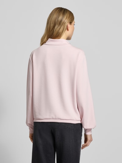 Frauenmodel trägt Sweatshirt mit Stehkragen und Brusttasche von monari in Rosa, weiche Textur, Regular Fit, Rückansicht Ganzkörperansicht.