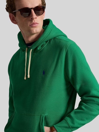 Männermodel trägt Regular Fit Hoodie aus Baumwoll-Mix von Polo Ralph Lauren in Grün, Optik: Unifarben, Logo-Detail, Kängurutasche, Kapuze mit Tunnelzug, Langarm, Ärmelabschluss und Rumpfabschluss gerippt, Materialverarbeitung: Sweat, Nahaufnahme Oberkörper.
