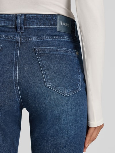 Frauenmodel trägt dunkelblaue Bootcut-Jeans aus Baumwoll-Mix Modell 'MARY' von Brax, strukturierte Textur, Ganzkörperansicht Rückansicht, Damen Bootcut-Jeans von Brax.