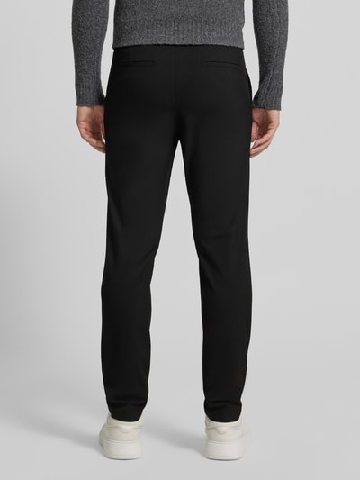 Männermodel trägt schwarze Chino mit Eingrifftaschen Modell 'ROBERT' von SELECTED HOMME aus Material-Mix mit Viskose-Anteil, Unifarbenes-Design, Körpernaher-Schnitt, Knopf- und Reißverschluss, Ganzkörperansicht Rückansicht.