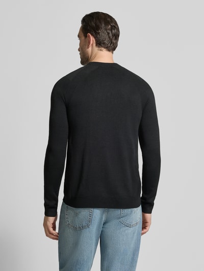 Męski model nosi Regular Fit Strickpullover mit Woll-Anteil od BOSS Green, czarny, strukturalny wzór, dżinsy, krój regular fit, widok całej sylwetki od tyłu.
