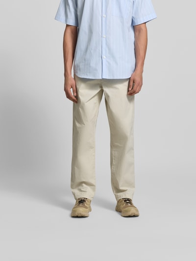 Männermodel trägt Straight Fit Stoffhose aus Baumwolle von ANNARR in Beige mit Eingriff- und Gesäßtaschen, Ganzkörperansicht von vorne.