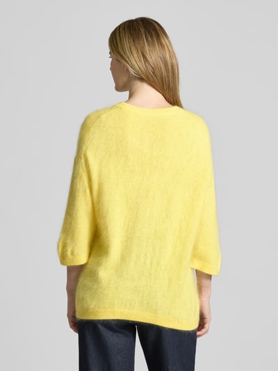 Kobiece modelka nosi Strickpullover aus Kaschmir-Baumwoll-Mix mit 3/4-Arm od HERZENS, krój regular fit, okrągły dekolt, długość pleców 63 cm, długość rękawa 30 cm, jasny żółty kolor, puszysta faktura, widok całej sylwetki z tyłu.