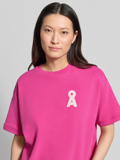 Frauenmodel trägt Oversized Sweatshirt aus reiner Baumwolle Modell 'BAMIKAA' von Armedangels, Optik: Unifarben, Passform: Oversized, Logo-Stitching, Crew Neck, Rundhals, Ärmelform: Kurzarm, Materialverarbeitung: Sweat, Farbe: Pink, Ganzkörperansicht von vorne.