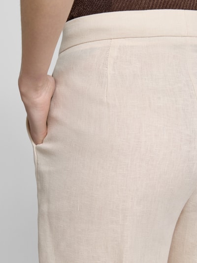 Frauenmodel trägt Stoffhose mit Bügelfalte Modell 'BORELI' von Mango, Reine Baumwolle, Slim-Fit, Beige, Nahaufnahme Oberkörper seitlich, strukturierte Optik.