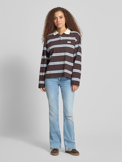 Frauenmodel trägt Flared Fit Jeans im Used-Look von Gina Tricot aus elastischem Baumwoll-Mix mit 5-Pocket-Design, Ganzkörperansicht von vorne.