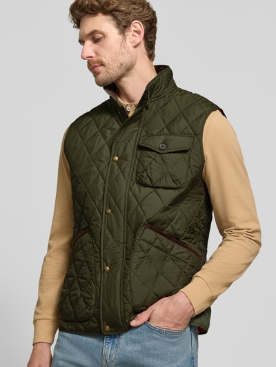 Męski model nosi oliwkowozieloną, pikowaną kamizelkę Regular Fit Weste mit Logo-Patch model 'BEATON' od Polo Ralph Lauren, widok całej sylwetki z przodu.