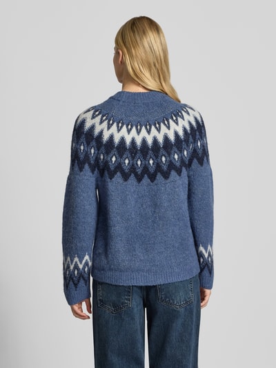 Vrouwenmodel draagt Relaxed Fit Pullover met wol-aandeel model 'Jacquard' van Gina Tricot, gebreide look, blauw met witte en donkerblauwe patronen, elastisch materiaal, ronde hals, ruglengte 60 cm, mouwlengte 43 cm, geheel achteraanzicht.