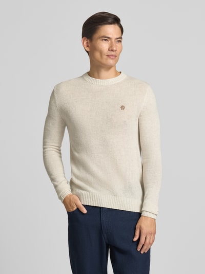 Männermodel trägt Slim Fit Strickpullover aus reiner Wolle mit Label-Stitching von MCNEAL, helle Farbe, gerippte Abschlüsse, Ganzkörperansicht von vorne.