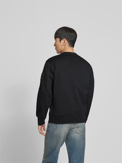 Männermodel trägt Sweatshirt mit Rundhalsausschnitt von Moose Knuckles in Schwarz, Regular-Fit, Reine Baumwolle, Logo-Detail, Rückenlänge 69 cm, Ganzkörperansicht Rückansicht.