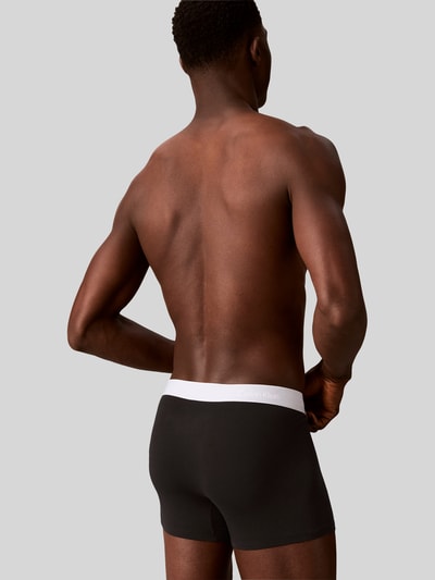 Männermodel trägt Regular Fit Trunks aus Baumwoll-Mix im 3er-Pack von Calvin Klein Underwear, mehrfarbig, mit Logo-Bund, Ganzkörperansicht Rückansicht.