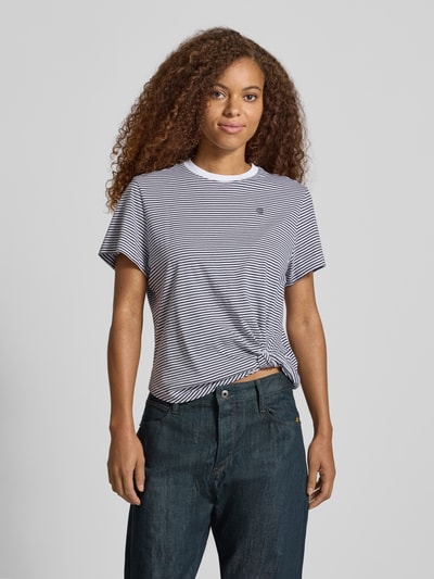 Frauenmodel trägt Relaxed Fit T-Shirt aus reiner Baumwolle mit geknotetem Saum von G-Star RAW, weiß-dunkelblau gestreift, Ganzkörperansicht von vorne.