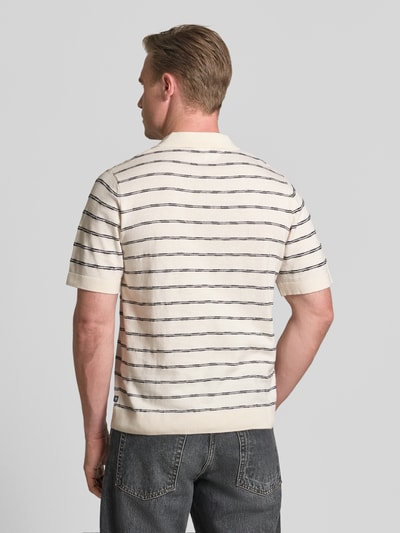 Männermodel trägt Regular Fit Poloshirt aus reiner Baumwolle von Tom Tailor in Creme mit dunkelblauen Streifen, Ganzkörperansicht Rückansicht.