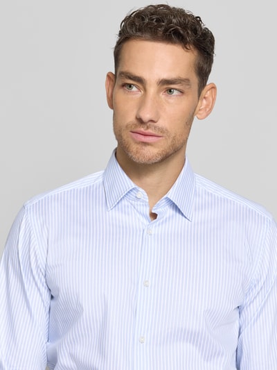 Męski model nosi Regular Fit Businesshemd aus Baumwoll-Mix von BOSS, efekt: wzór na całej powierzchni, krój regular fit, kształt kołnierza: kołnierzyk typu kent, zapięcie: listwa guzikowa jednorzędowa, zbliżenie na górną część ciała.