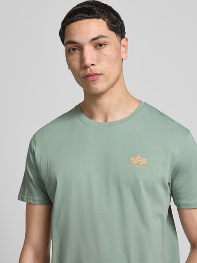Männermodel trägt T-Shirt mit Label-Details Modell 'BASIC' von Alpha Industries in Grün, Reine Baumwolle, Gerader-Schnitt, Nahaufnahme Oberkörper.