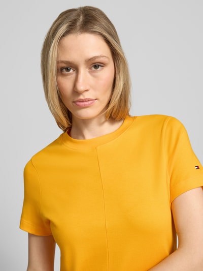 Frauenmodel trägt Midikleid aus reiner Baumwolle von Tommy Hilfiger, Optik: Unifarben, Passform: Regular-Fit, Rundhals, Logo-Stitching, Ärmelform: Kurzarm, Materialverarbeitung: Interlock, Nahaufnahme Oberkörper.