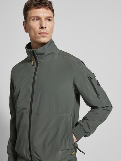 Männermodel trägt Windbreaker mit Stehkragen Modell 'YETUR' von CARS JEANS in Grau, Reißverschluss, Reißverschlusstasche, Nahaufnahme Oberkörper. Material-Mix mit Stretch, elastische Abschlüsse, gerader Schnitt.