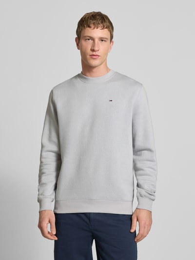 Männermodel trägt Regular Fit Sweatshirt aus Baumwoll-Mix von Tommy Jeans in Optik: Unifarben mit Logo-Stitching, Ganzkörperansicht von vorne.