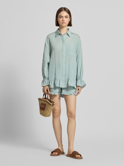 Frauenmodel trägt Bluse aus Viskose-Mix mit Brusttasche Modell 'Selina' von OH APRIL, mintgrün, Rüschenärmel, Rüschensaum, Streifenstruktur, Hemdblusenkragen, verdeckte Knopfleiste, Straight Fit, Damen Bluse, Länge bei Größe S 73 cm, Ärmellänge 61 cm, Ganzkörperansicht von vorne.