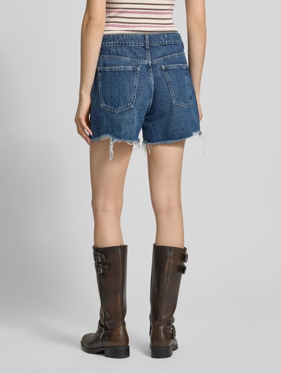 Frauenmodel trägt Jeansshorts im Used-Look und mit 5-Pocket-Design von REVIEW aus reiner Baumwolle in Blau, Loose-Fit, Ganzkörperansicht Rückansicht.