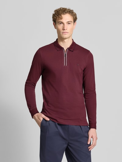 Männermodel trägt Slim Fit Poloshirt mit Reißverschluss von Christian Berg Men in Bordeaux, reine Baumwolle, Longsleeve, Ganzkörperansicht von vorne.