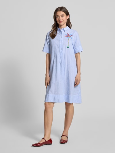 Frauenmodel trägt Knielanges Hemdblusenkleid mit Motiv-Print von Milano Italy aus Reine Baumwolle, Gerader-Schnitt, Knielänge, Knopfleiste, 1/2-Arm, hellblau mit buntem Motiv-Print, Ganzkörperansicht von vorne.
