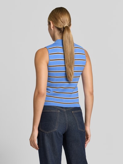 Frauenmodel trägt Regular Fit Poloshirt aus Viskose-Mix von MANGO, blau mit braun-weißen Streifen, Strukturmuster, ärmellos, Ganzkörperansicht Rückansicht.