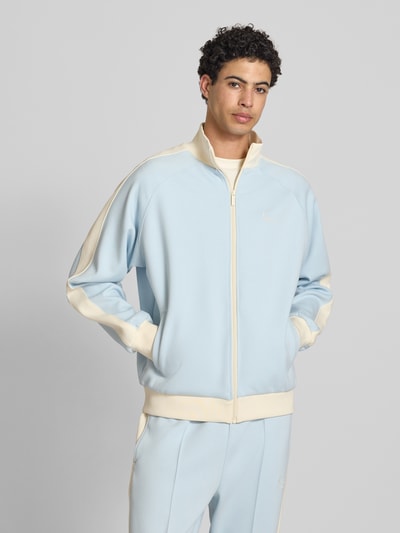 Männermodel trägt Regular Fit Sweatjacke mit Logo-Stitching von KARL KANI in Hellblau-Creme, Elastischer-Material-Mix, Stehkragen, Reißverschluss, Eingrifftaschen, elastische Abschlüsse, Rückenlänge 65 cm, Ärmellänge 74 cm, Ganzkörperansicht von vorne.