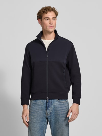 Männermodel trägt Regular Fit Jacke aus Baumwoll-Mix Modell 'FELPA' von Armani Exchange in Dunkelblau, Ganzkörperansicht von vorne, elastische Abschlüsse, Stehkragen, Zweiwege-Reißverschluss, Rückenlänge 66 cm, Ärmellänge 63 cm.