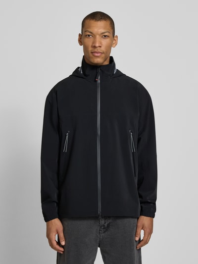 Männermodel trägt Jacke mit Zweiwege-Reißverschluss Modell 'YUPP-T' von FIRE + ICE in Schwarz, Reißverschlusstaschen, Kapuze, Ganzkörperansicht von vorne.