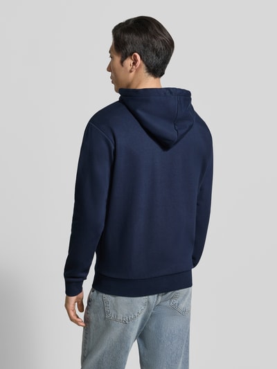 Männermodel trägt Regular Fit Sweatjacke aus Baumwoll-Mix von Tom Tailor Denim in Dunkelblau, Kapuze, gerippte Bündchen, Rückansicht.