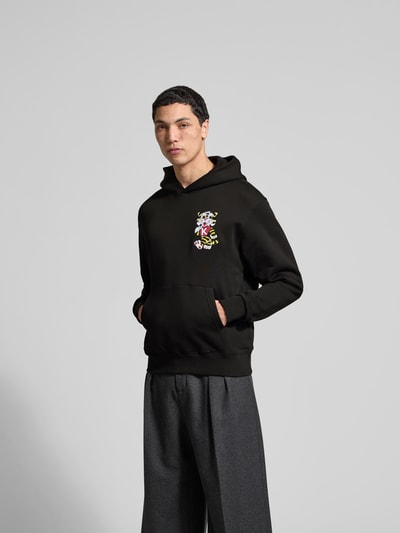 Männermodel trägt Oversized Hoodie aus reiner Baumwolle von Kenzo, schwarze Farbe, Label-Stitching, Känguru-Tasche, elastische Abschlüsse, lockere Passform, Herren Sweatshirt, Rückenlänge 66 cm bei Größe M, Ganzkörperansicht von vorne.