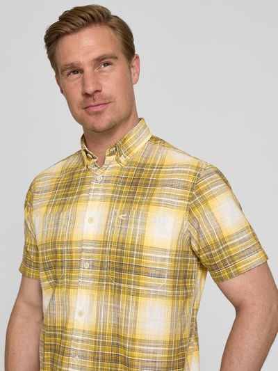 Mannenmodel draagt Slim Fit Freizeithemd met Logo-Stitching van camel active in geel-wit ruitdessin van puur katoen, kortemouw, borstzak, button-downkraag, doorlopende knoopsluiting, slim fit. Nahaufnahme bovenlichaam.