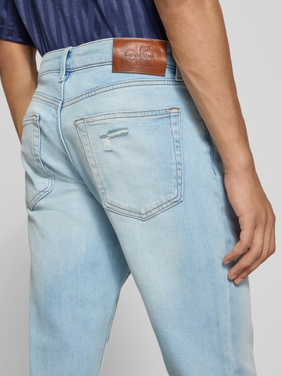 Männermodel trägt Slim Fit Jeans aus Baumwoll-Mix von Calvin Klein Jeans in hellem Blau mit Lederpatch, Ganzkörperansicht Rückansicht.