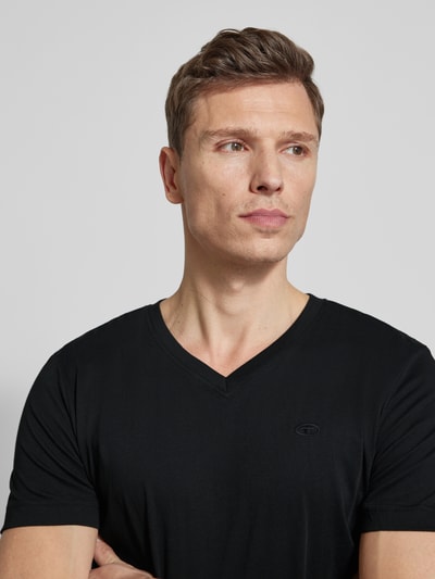 Männermodel trägt Regular Fit T-Shirt aus reiner Baumwolle von Tom Tailor in Schwarz, unifarben, Logo-Stitching, Nahaufnahme Oberkörper.