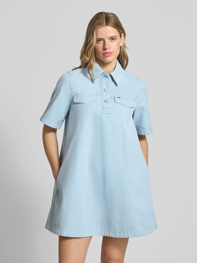 Frauenmodel trägt Oversized Minikleid aus reiner Baumwolle von Tommy Jeans in Optik: Unifarben, Passform: Oversize, Mini-Länge, Hochgeschlossen, mit Logo-Stitching, kurze Knopfleiste, Ärmelform: Kurzarm, Material: Reine Baumwolle, Ganzkörperansicht von vorne.