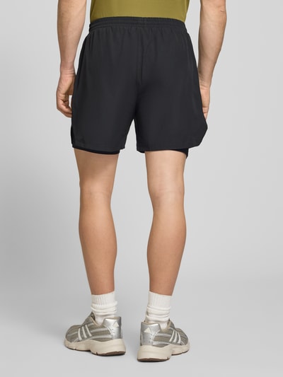 Männermodel trägt Shorts im 2-in-1-Look von HALO in Schwarz, Material-Mix mit Stretch, elastischer Bund, Ganzkörperansicht Rückansicht.