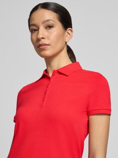 Frauenmodel trägt Slim Fit Poloshirt mit Knopfleiste von Christian Berg Woman aus Baumwoll-Elasthan-Mix in Rot, Nahaufnahme Oberkörper.