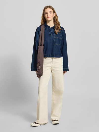 Vrouwenmodel draagt Loose Fit Jeansbluse aus reiner Baumwolle van Marc O'Polo Denim, uni donkerblauwe denim, borstzak, lange mouwen, voorkant totaalbeeld.