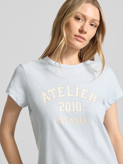 Frauenmodel trägt Regular Fit T-Shirt mit Logo-Print von MOS MOSH in feinem hellblauen Streifenmuster, Reine Baumwolle, Rundhalsausschnitt, Rückenlänge bei Größe S 63 cm, Nahaufnahme Oberkörper.