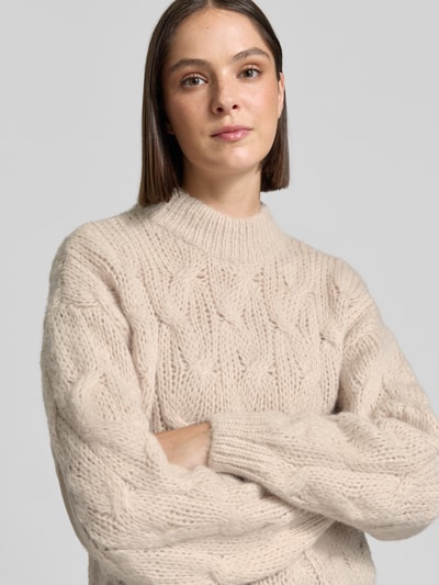 Frauenmodel trägt Regular Fit Pullover mit Rundhalsausschnitt Modell 'MAYBE' von VERO MODA in Beige mit Strickstruktur, Nahaufnahme Oberkörper.