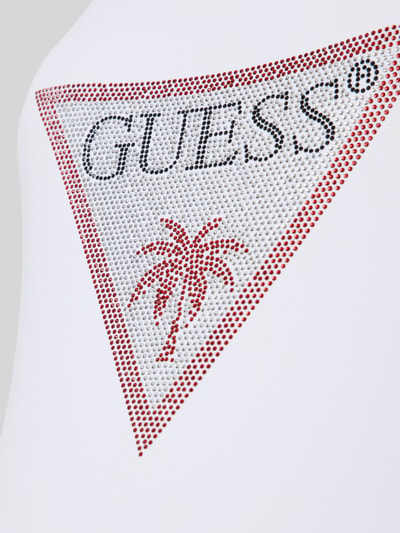 Frauenmodel trägt Slim Fit Badeanzug mit Strasssteinbesatz von Guess aus Elastischer-Material-Mix, Logo-Detail, Nahaufnahme Oberkörper.