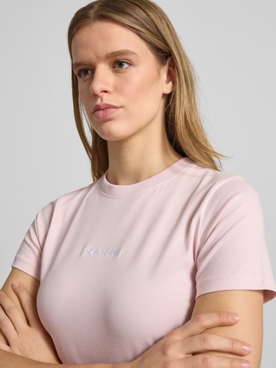 Kobiece model nosi Cropped T-Shirt mit Label-Stitching von Pegador, mieszanka bawełny i elastanu, krój krótki, okrągły dekolt, wyhaftowane logo, długość tyłu w rozmiarze S: 41 cm, pastelowy róż, gładka faktura, Nahaufnahme Oberkörper