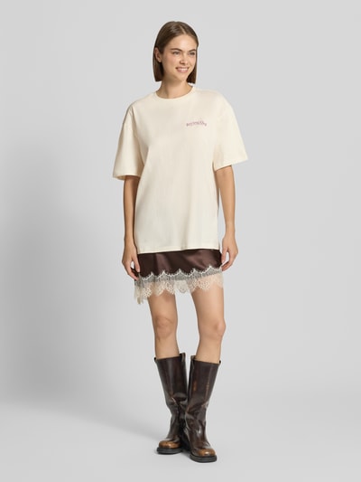 Frauenmodel trägt Oversized Fit T-Shirt aus reiner Baumwolle mit Label-Detail von REVIEW, cremefarbener Stoff, Ganzkörperansicht von vorne.
