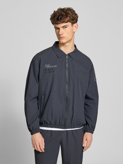 Männermodel trägt Regular Fit Hemdjacke mit Logo Modell 'HALO MOVE' von HALO in Dunkelgrau, glatte Textur, Reißverschluss, Ganzkörperansicht von vorne. Rückenlänge 66 cm, Ärmellänge 61 cm, Umlegekragen, Herren Hemdjacke.
